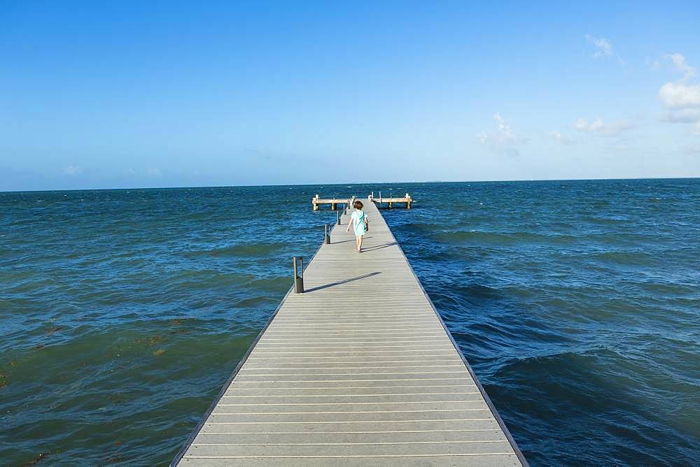 5 year old boy walking on a pier, view to the horizon, Grand Cayman, Cayman Islands