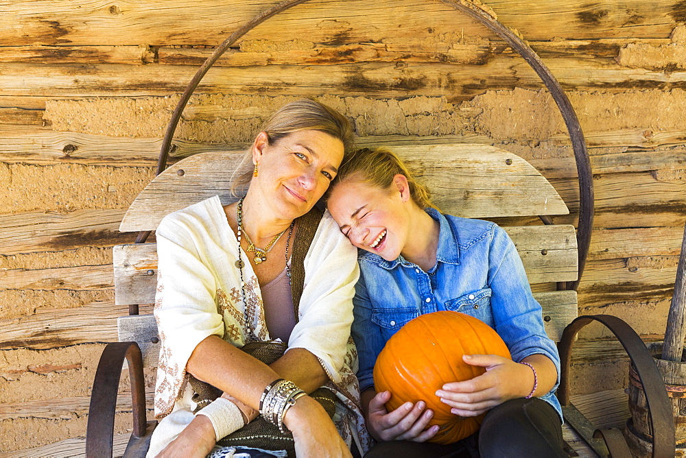 portrait of mother and her teen age daughter holding pumpkin