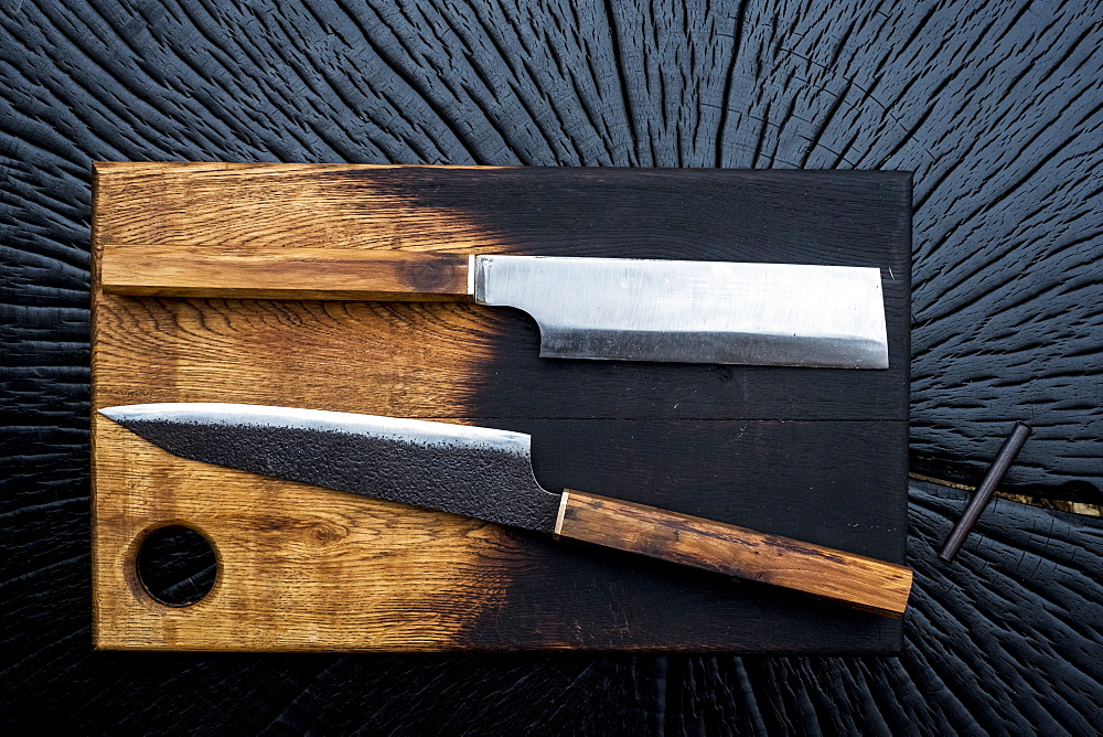 High angle close up of two handmade knives on wooden cutting board