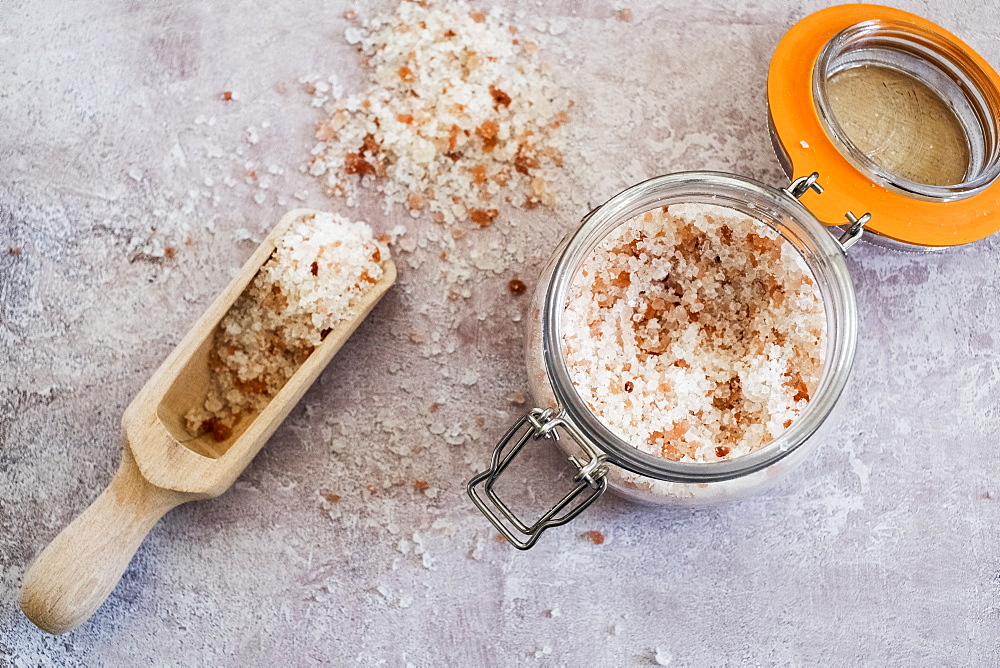 High angle close up of wooden spoon and glass jar with coarse salt