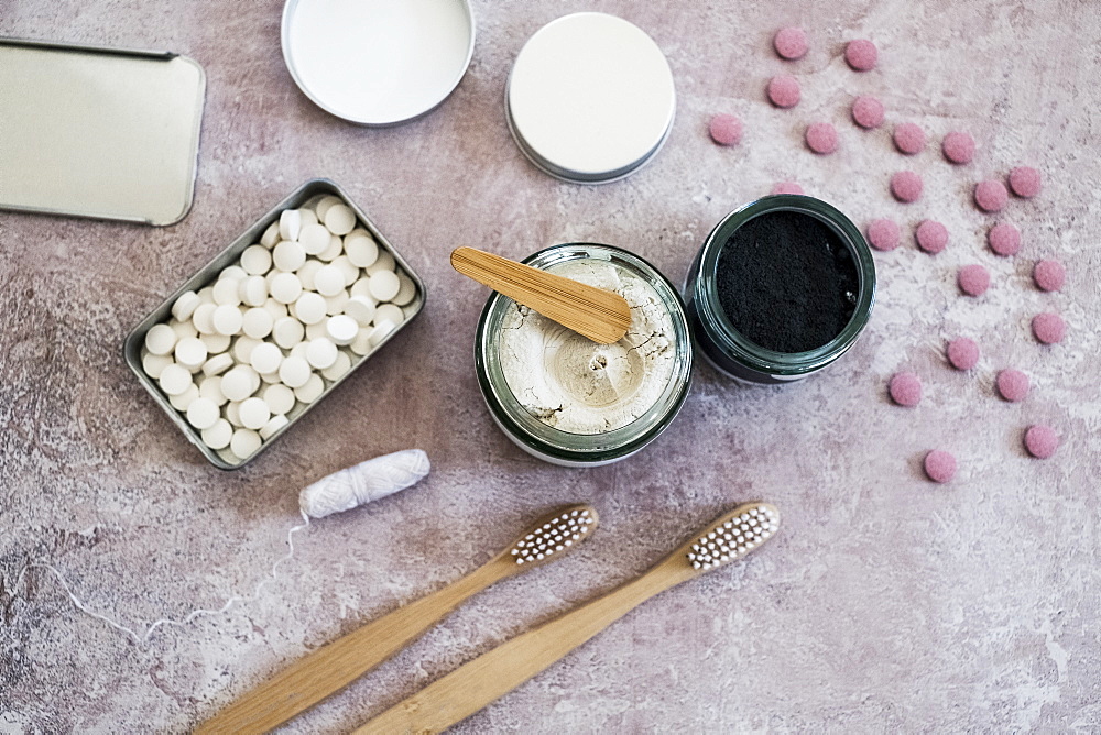 High angle close up of wooden toothbrushes, homemade cosmetics and pills in metal box