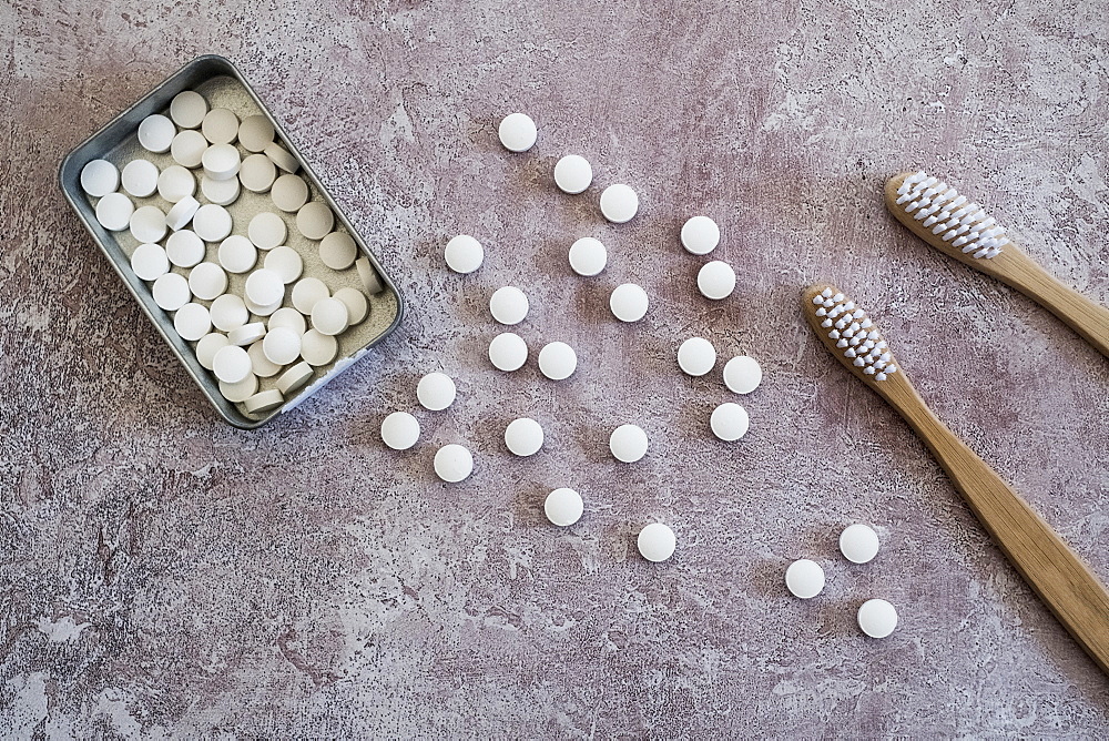 High angle close up of two wooden toothbrushes and pills in metal box