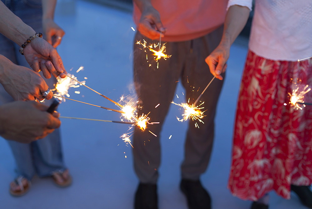 Group of young men and women with sparklers on a rooftop in an urban setting, Fukuoka, Kyushu, Japan