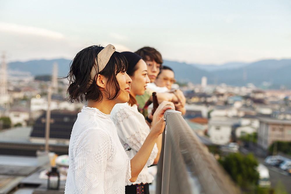 Group of young Japanese men and women standing on a rooftop in an urban setting, Fukuoka, Kyushu, Japan