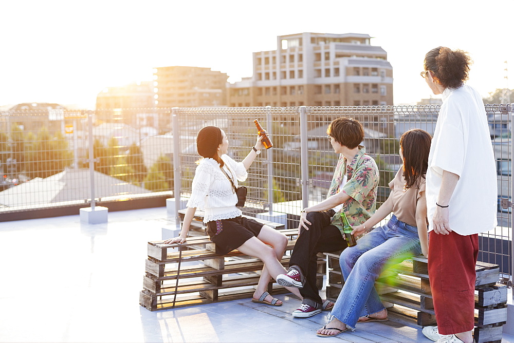 Group of young Japanese men and women sitting on a rooftop in an urban setting, Fukuoka, Kyushu, Japan