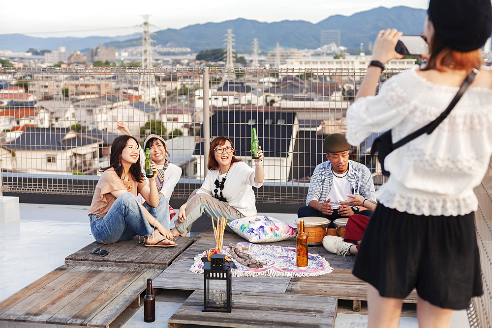 Smiling group of young Japanese men and women on a rooftop in an urban setting, Fukuoka, Kyushu, Japan