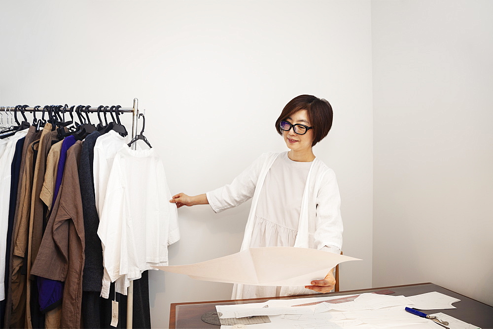 Japanese woman wearing glasses working at a desk in a small fashion boutique, Kyushu, Japan