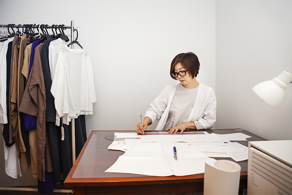 Japanese woman wearing glasses working at a desk in a small fashion boutique, Kyushu, Japan