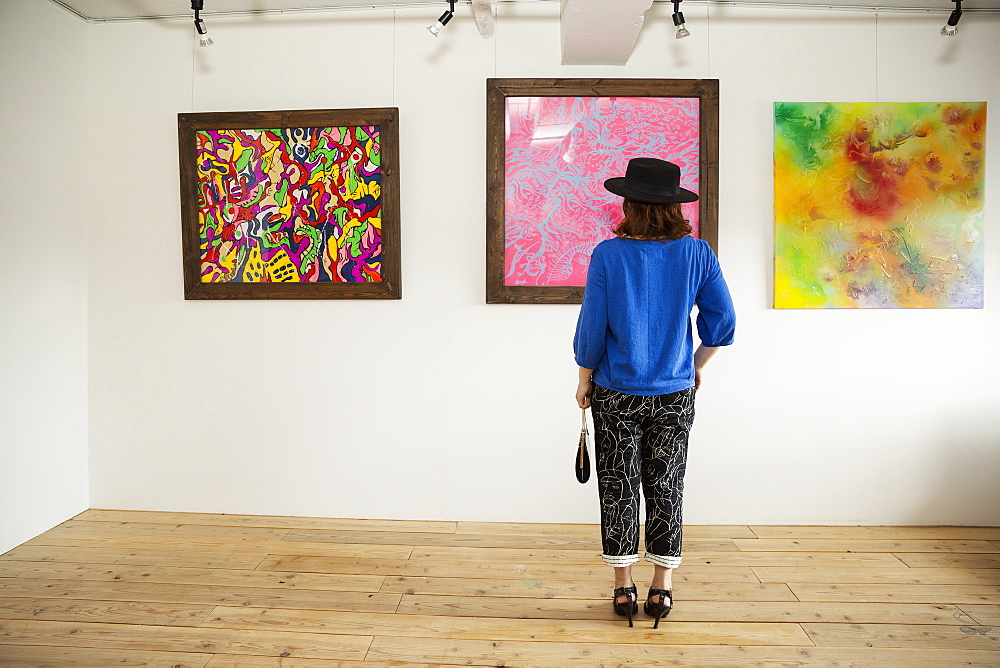 Japanese woman wearing hat standing in front of abstract painting in an art gallery, Kyushu, Japan