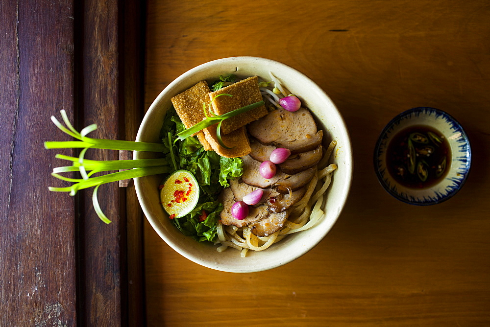 High angle close up of bowl of Cao lau noodles, a specialty dish with noodles made from local well water in Hoi An, Vietnam