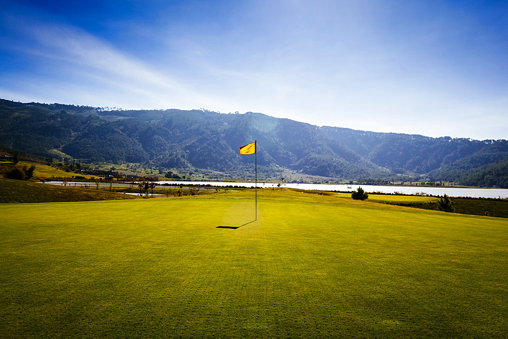 Flag on a golf course with sea and mountains in the distance, Vietnam