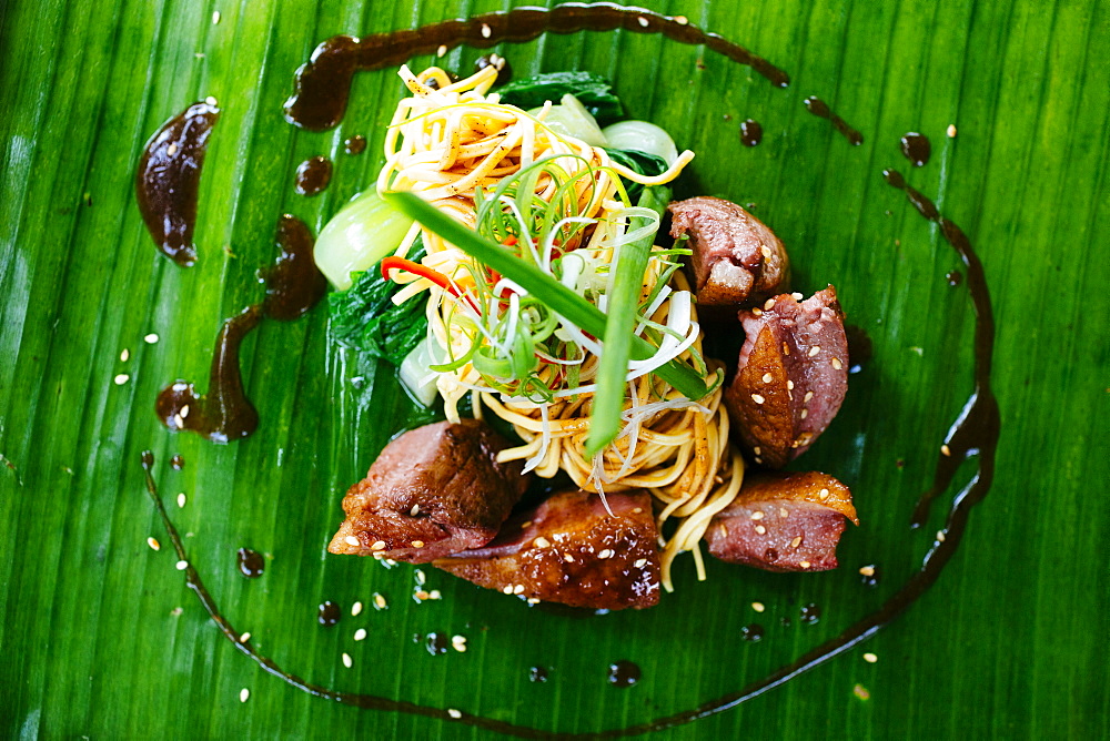 High angle view of seared duck breast and noodles served on a banana leaf, Vietnam