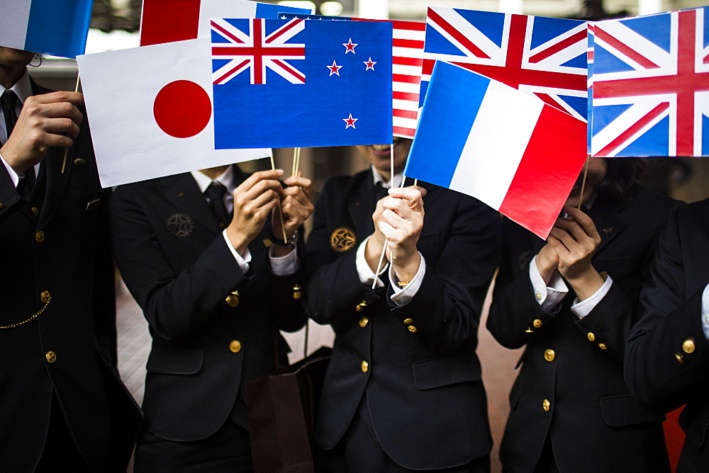 Close up of people in uniform waving small national flags, Kyushu, Japan