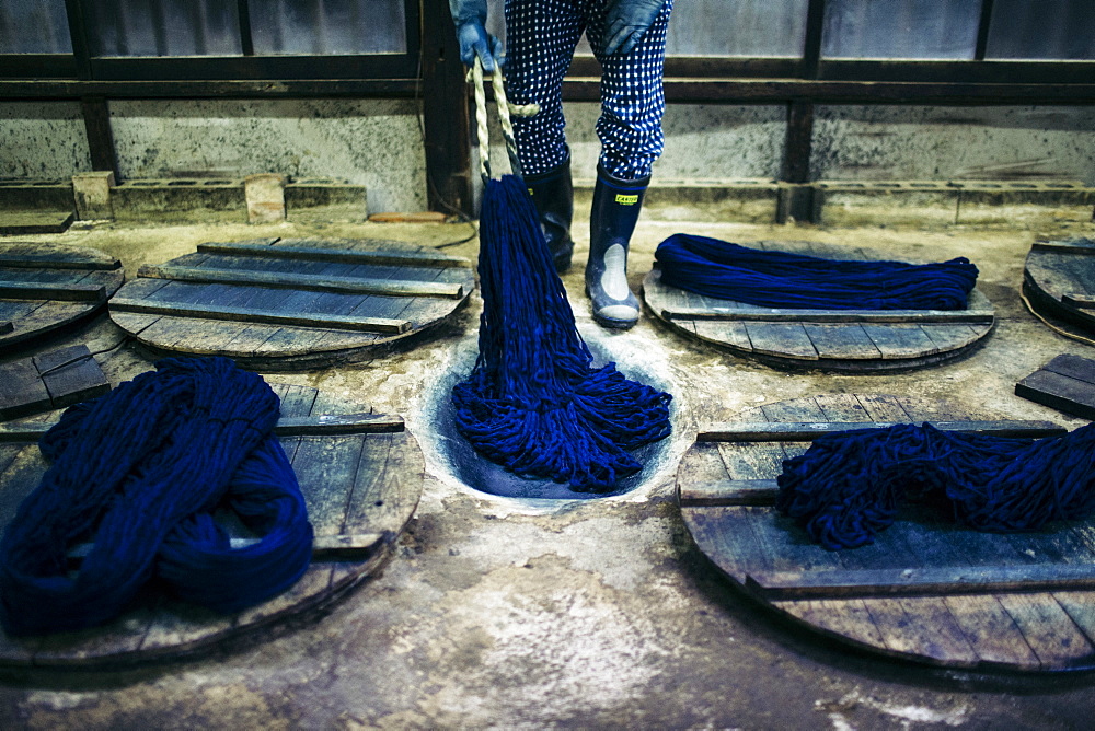 Close up of man beating indigo dye into strands of cotton, Kyushu, Japan