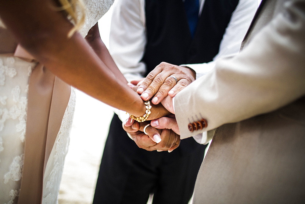 Close up of a husband and wife joining hands during the ceremony at a beach, Thailand