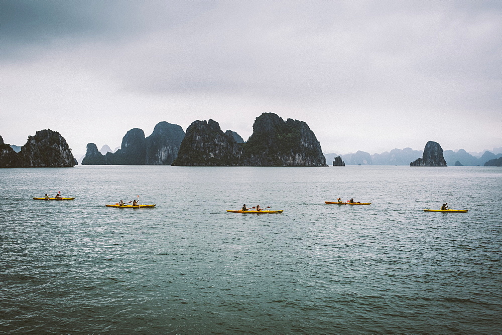 Group of kayakers rowing in a bay amidst limestone karst formations, Vietnam