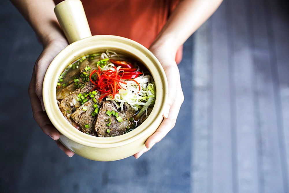 High angle close up of person holding bowl of Bun Bo Hue, Vietnam