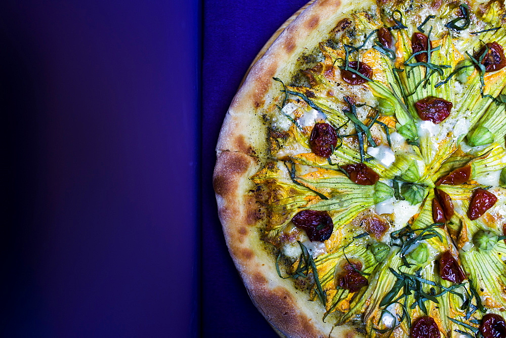 High angle close up of vegetarian pizza with goat cheese and zucchini flowers, Vietnam