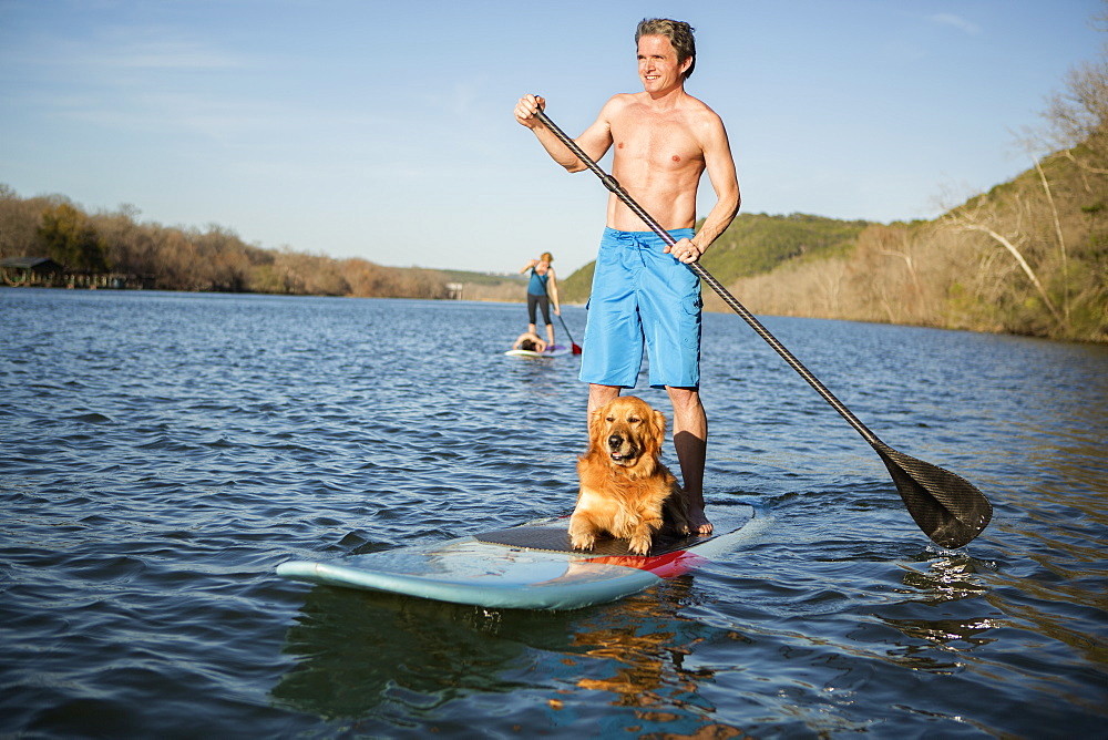 A man standing on a paddleboard with a dog, Austin, Texas, USA