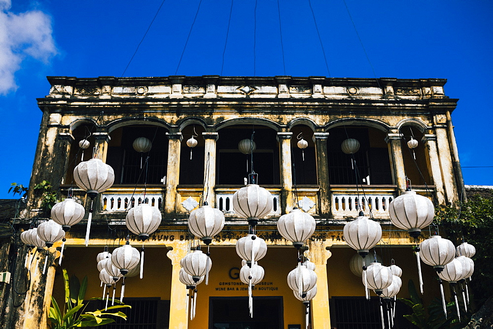 Traditional white lanterns hanging in front of an historic building, Vietnam