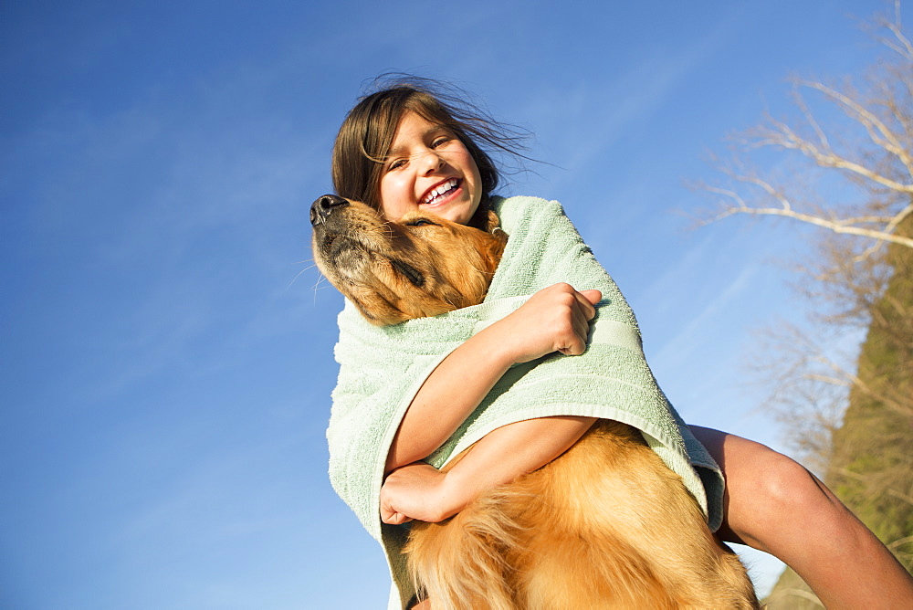 A girl in a beach towel with a golden retriever dog, Austin, Texas, USA