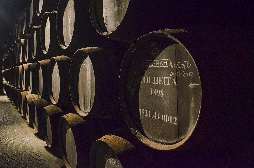 Close up of wooden barrels of Colheita port stacked in a cellar. Port wine production, Porto, Portugal