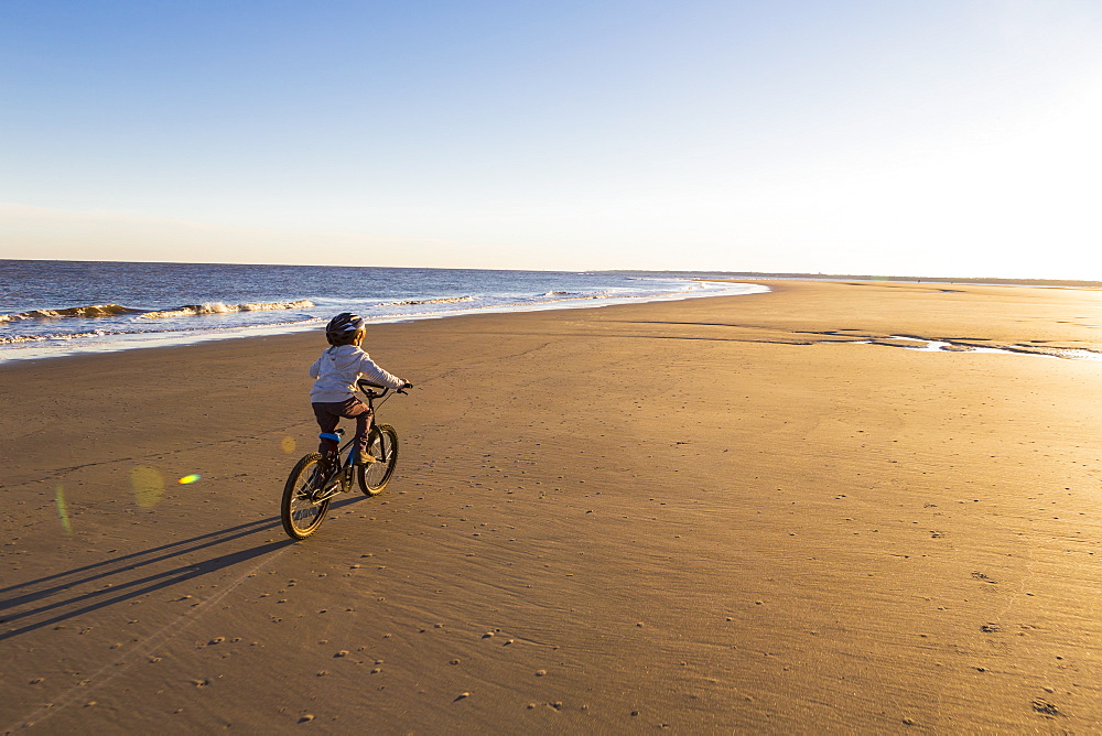 A young boy riding a bicycle on the beach, St Simon's Island, Georgia, United States