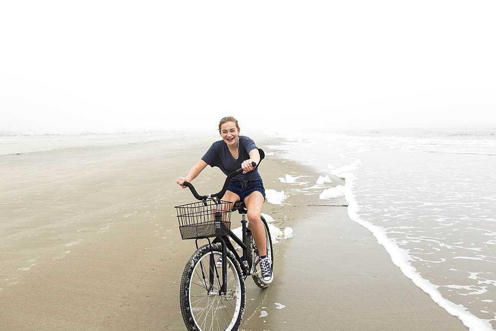 Teenage girl riding a bike on sand at the beach, St Simon's Island, Georgia, United States