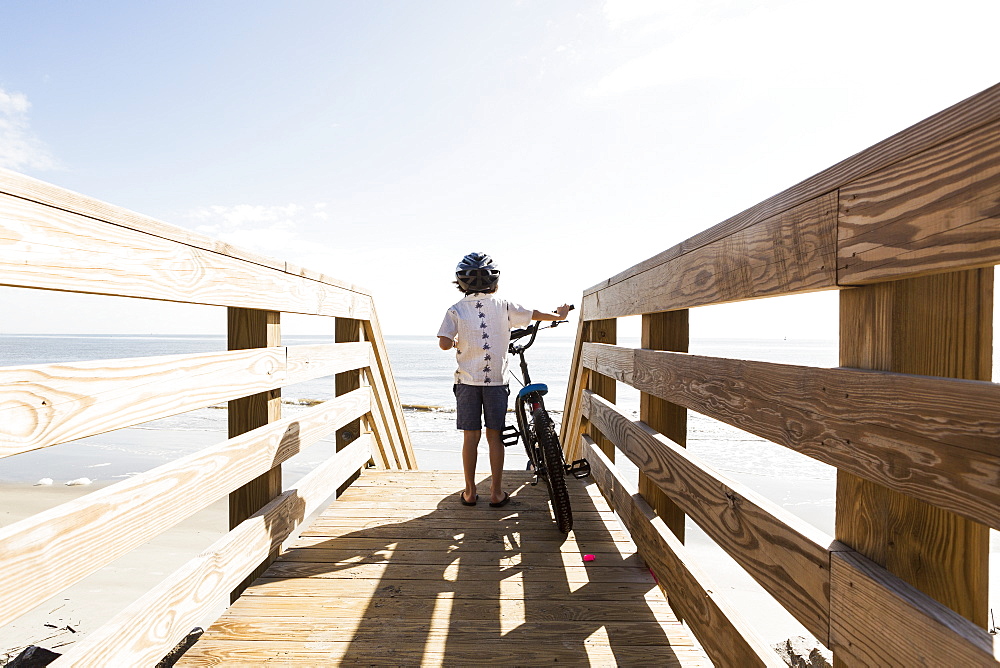 A young boy on wooden bridge with his bike, St Simon's Island, Georgia, United States