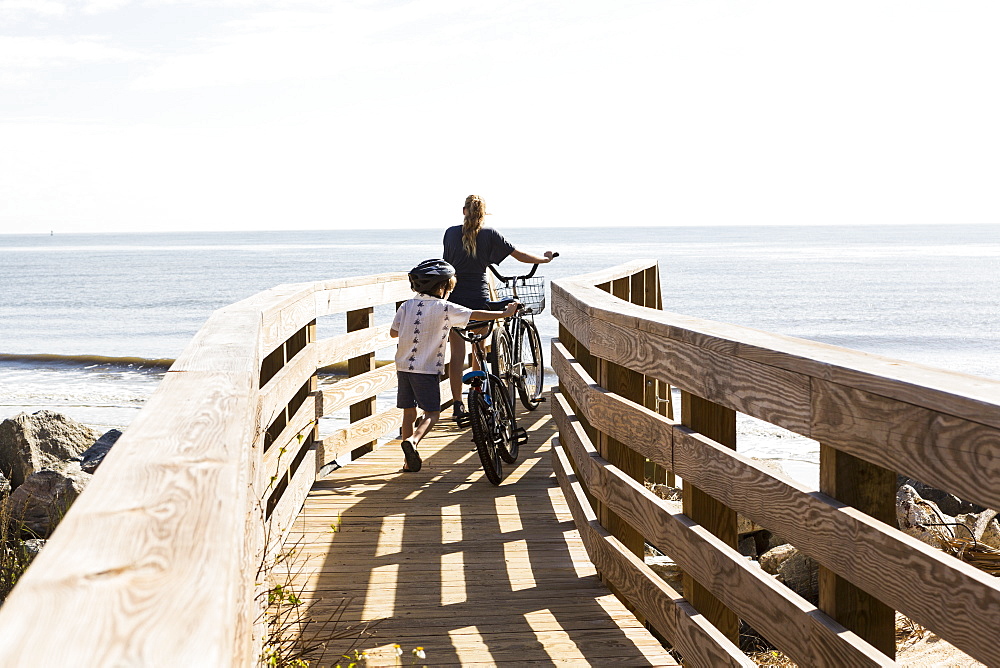 Two children, brother and sister on wooden bridge with bikes, St Simon's Island, Georgia, United States