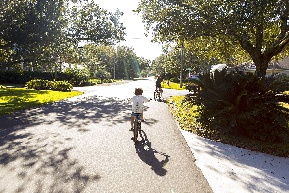 Children, a pre teenager and her brother cycling on a suburban road, St Simon's Island, Georgia, United States