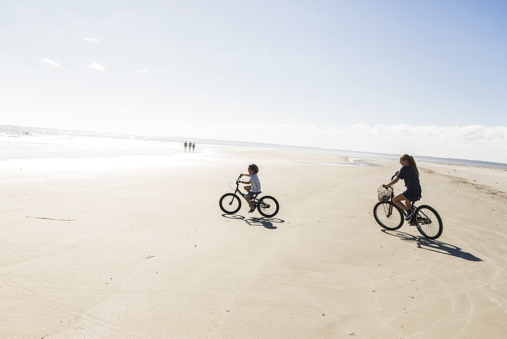 Two children cycling on an open beach, a boy and girl, St Simon's Island, Georgia, United States