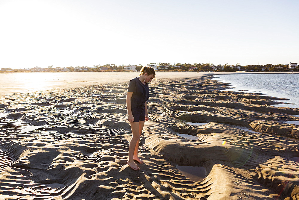 A teenage girl playing in sand dunes, at the beach, St Simon's Island, Georgia, United States
