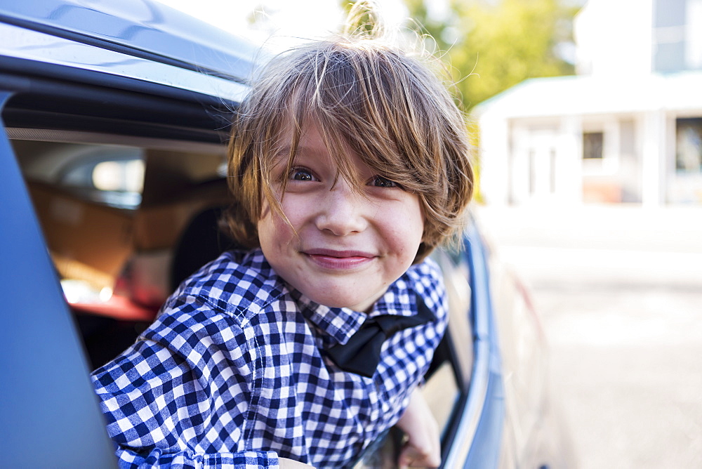 A six year old boy smiling at camera, looking out of car window, St Simon's Island, Georgia, United States