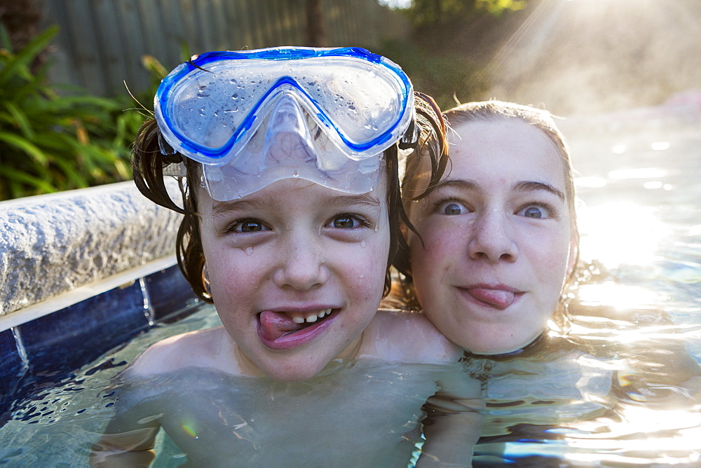 A teenage girl and brother in a warm pool, looking at the camera, sticking their tongues out, St Simon's Island, Georgia, United States