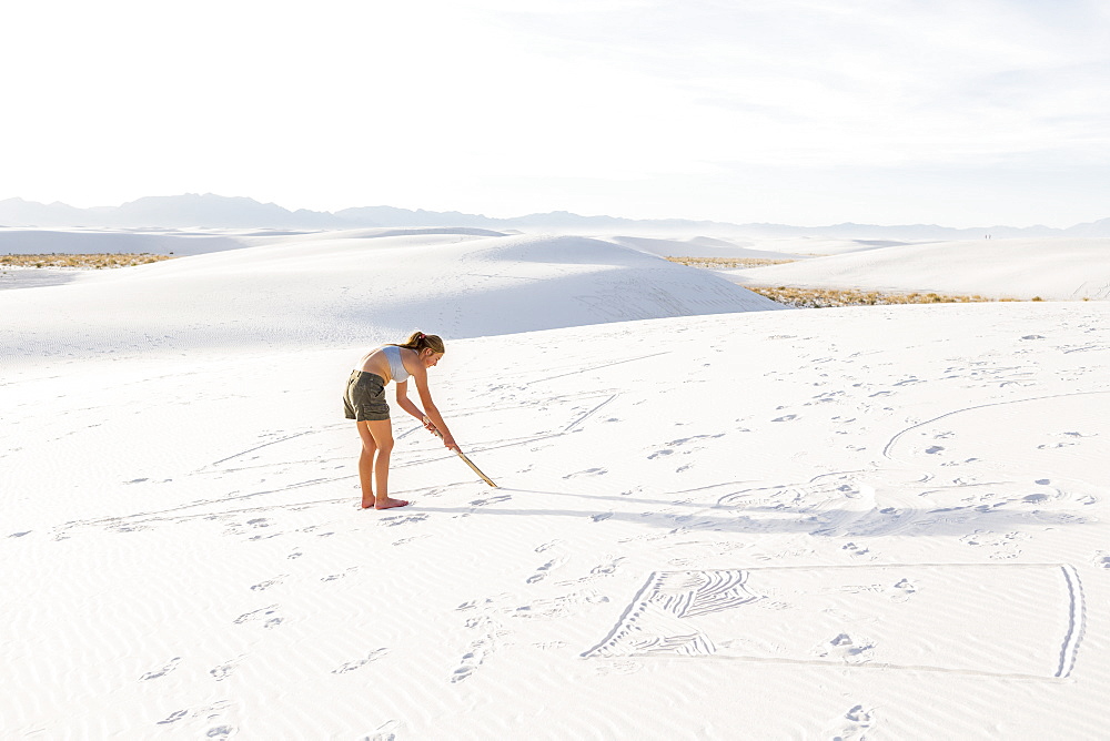 A teenage girl drawing in the sand, White Sands National Monument, New Mexico, United States