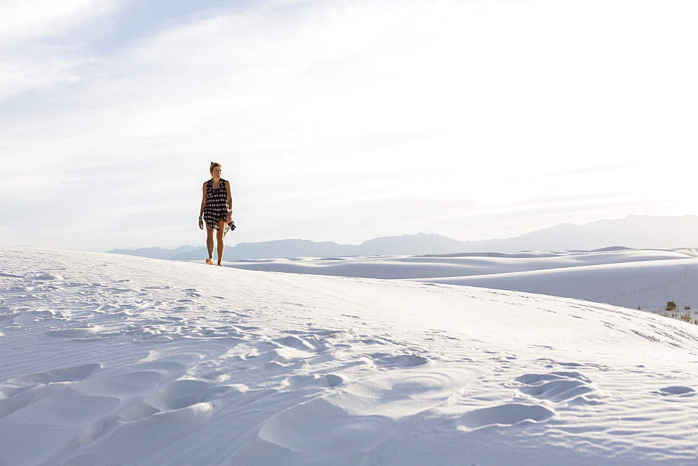 Woman walking in white sand dunes, White Sands National Monument, New Mexico, United States