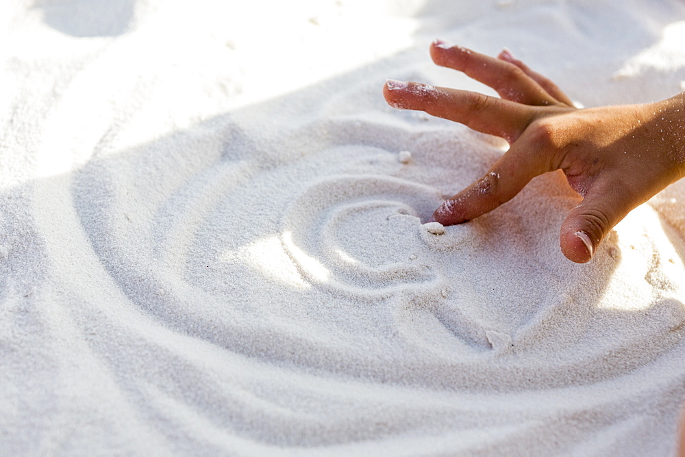 A boy drawing in the white sand with his hands, White Sands National Monument, New Mexico, United States