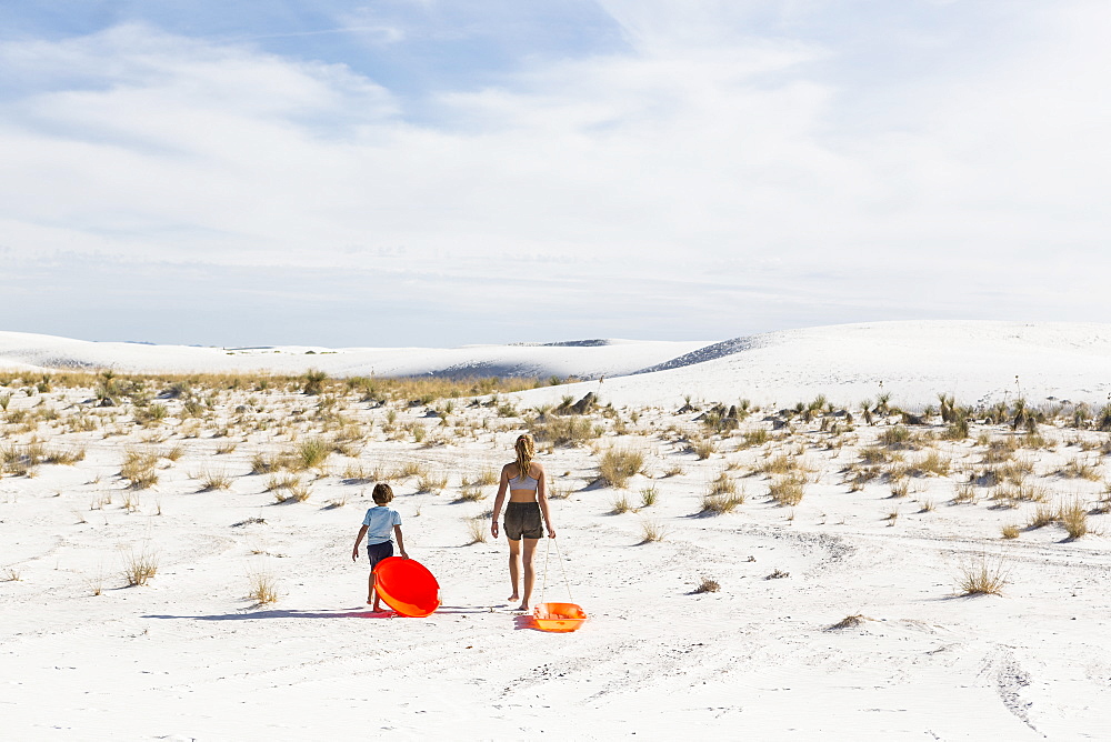 Two children pulling sledges, White Sands National Monument, New Mexico, United States