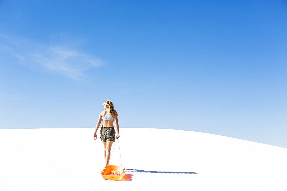 A teenage girl pulling a sled, White Sands National Monument, New Mexico, United States