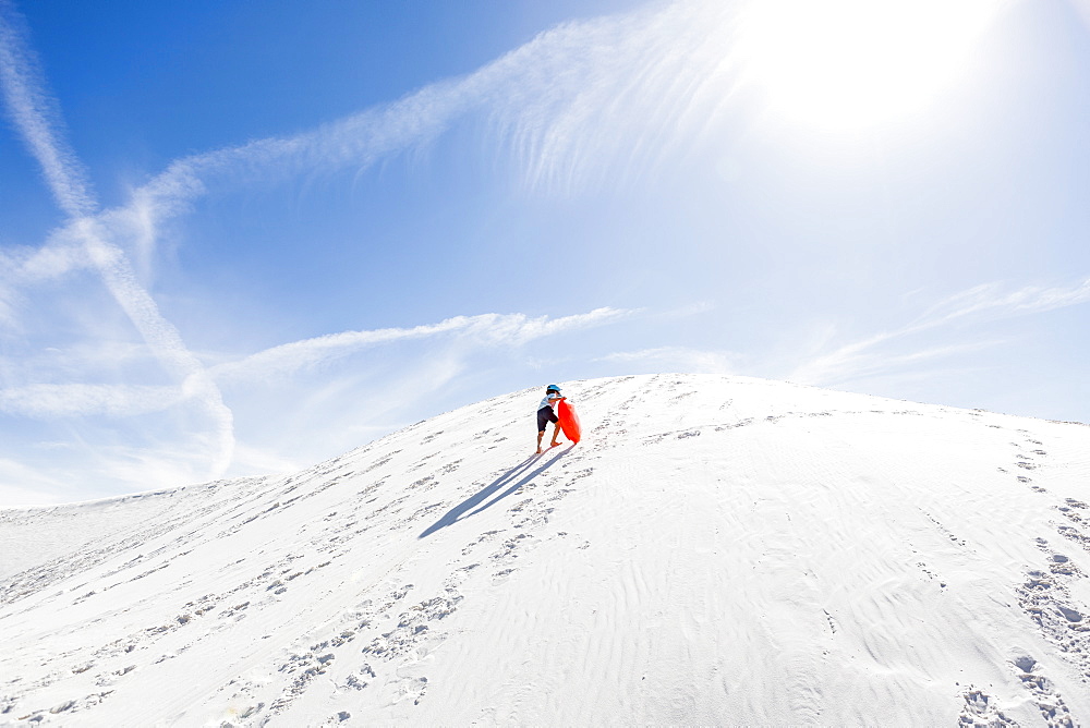 A young boy climbing sand dune, White Sands National Monument, New Mexico, United States