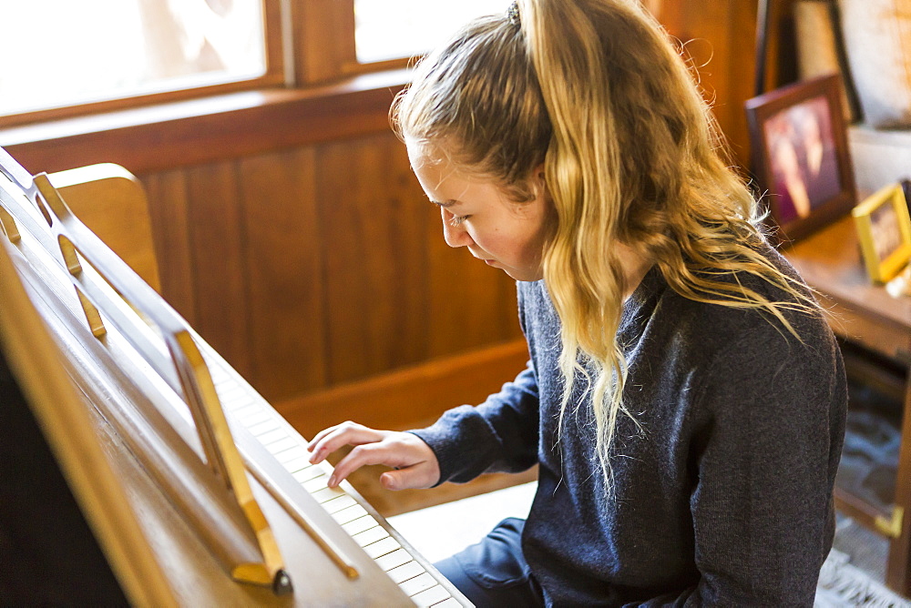 Teenage girl playing piano, practising.