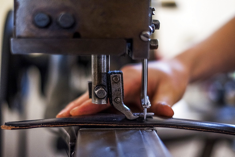 Close up of person sewing piece of leather to make a saddle, Berkshire, United Kingdom