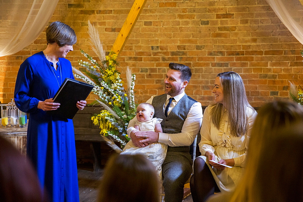 Celebrant performing naming ceremony for parents and their baby daughter in an historic barn