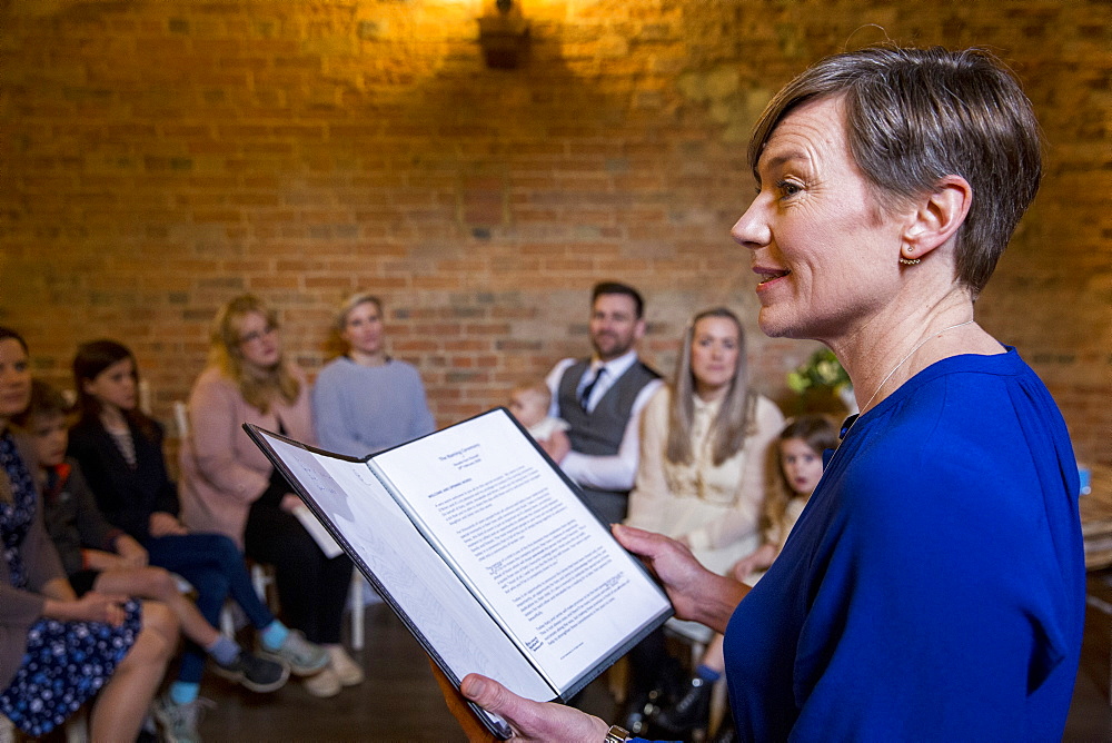 Celebrant performing naming ceremony for parents and their baby daughter in an historic barn