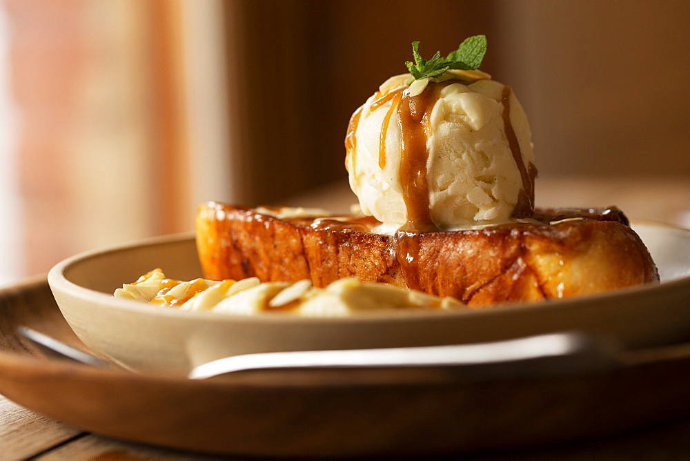 Close up of French toast with sliced banana and ice cream in a cafe