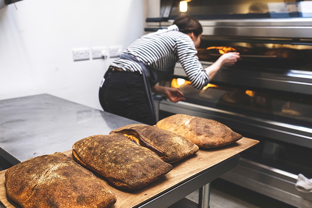 Artisan bakery making special sourdough bread, a baker checking the baked loaves