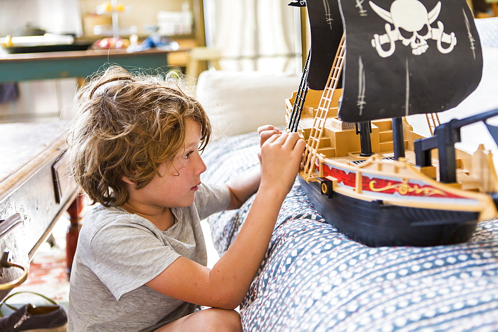 6 year old boy playing with a toy pirate ship at home