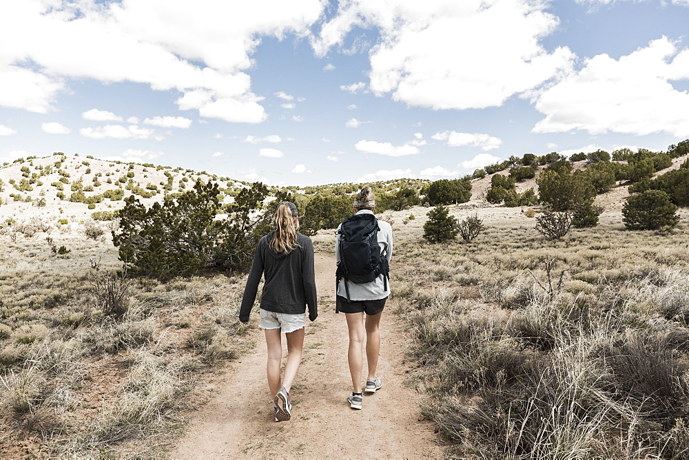 Rear view of adult woman and her teenage daughter hiking in the Galisteo Basin, New Mexico, United States of America