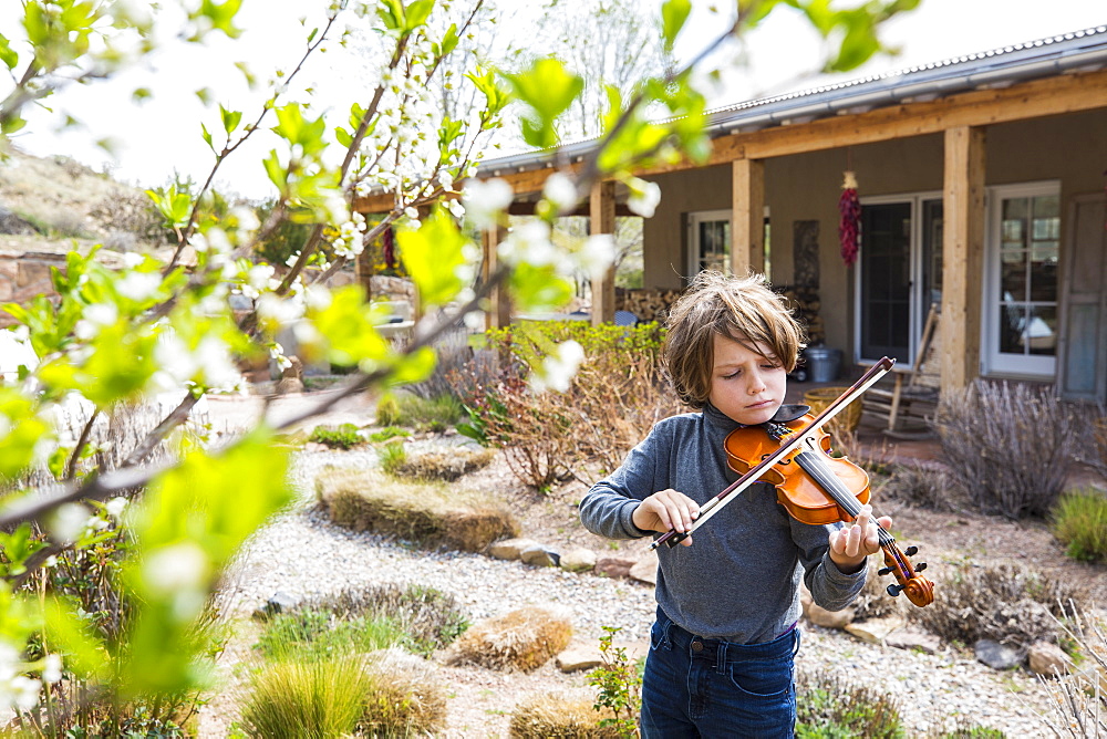 6 year old boy playing violin outside of his home